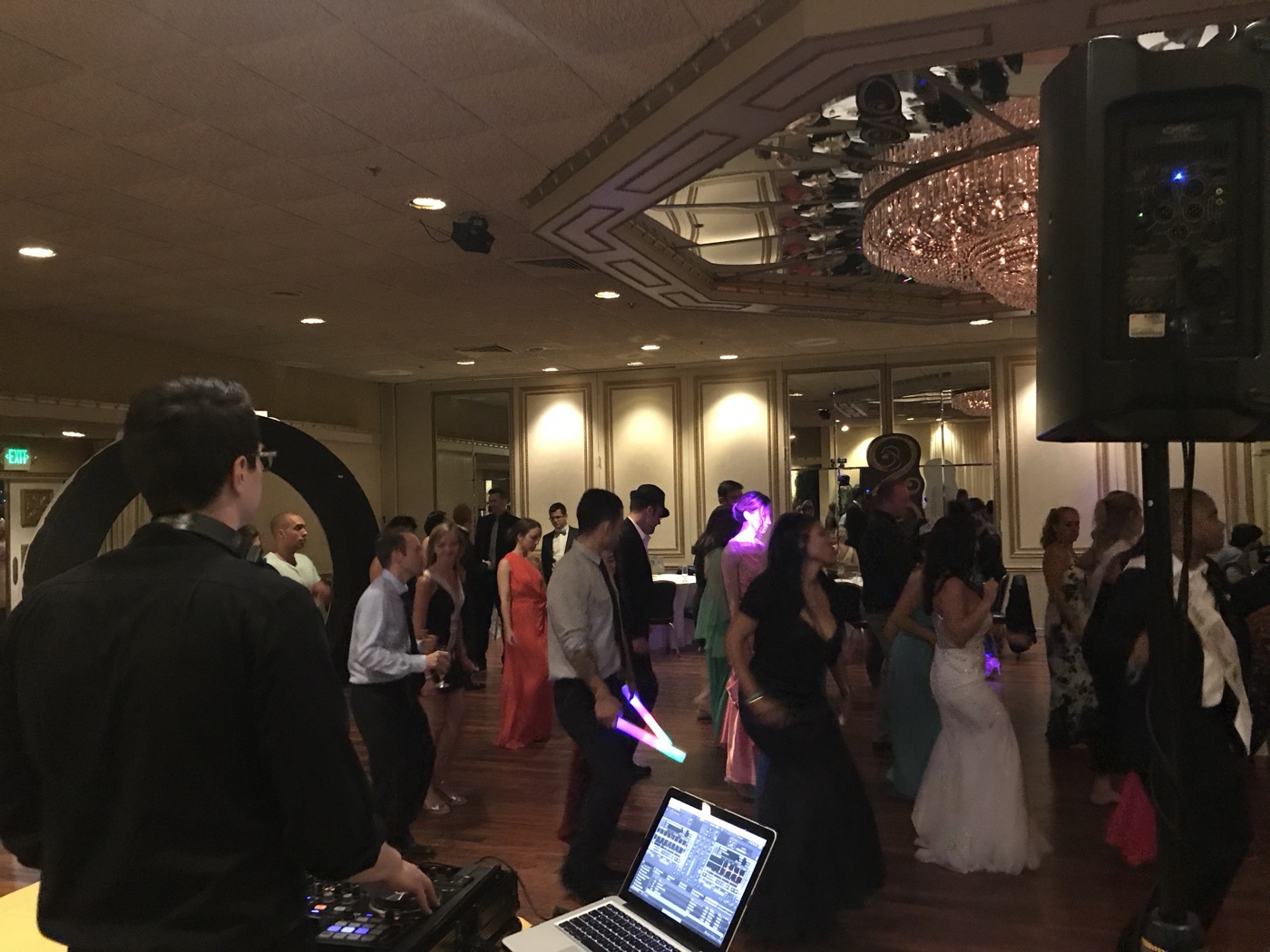A packed wedding dance floor under chandeliers